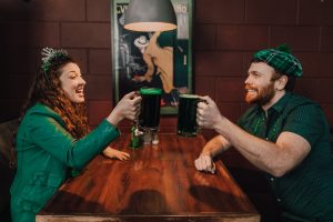Die 12 Pubs of Christmas, Pärchen in grünen Sachen stößt in Pub mit Guinness an