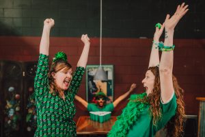 Die 12 Pubs of Christmas, feiernde Frauen in grünen Irlandsachen