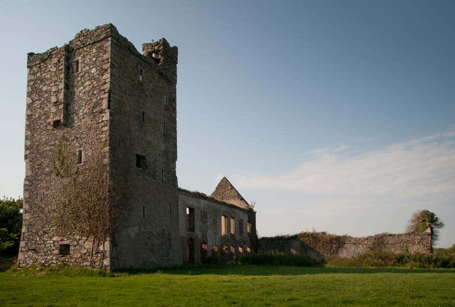 Sehenswürdigkeiten um Tacumshane Windmühle: Historisches Wahrzeichen in in Wexford. Auf dem Bild ist das Sigginstown castle mit seinem viereckigen großen steinernen Turm unter blauem Himmel zu sehen